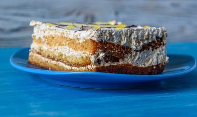 A slice of sponge cake on a plate on a wooden table photographed close up.