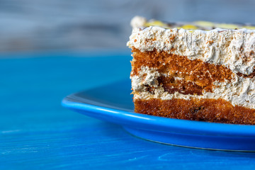 A slice of sponge cake on a plate on a wooden table photographed close up.