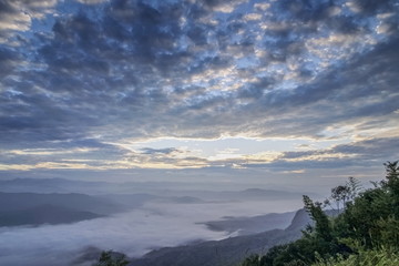Naklejka na ściany i meble Mountain view morning of the hills around with sea of mist cover with cloudy sky background, sunrise at Doi Samur Dao, Sri Nan National Park, Nan, Thailand.