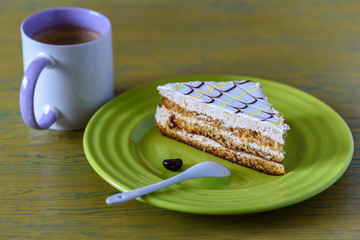 A slice of sponge cake on a plate on a wooden table photographed close up.