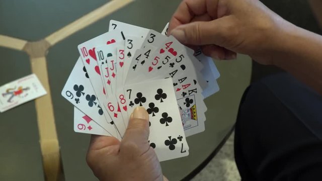 A group of people playing cards. Point of view of a man who holds playing cards in his hand.
