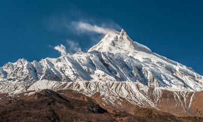 View of snow covered peak of Mount Manaslu (8 156 meters) with clouds in Himalayas, sunny day at Manaslu Glacier in Gorkha District in northern-central Nepal