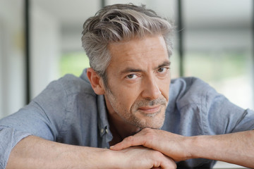 Fototapeta premium Portrait of handsome mature man looking at camera in contemporary home