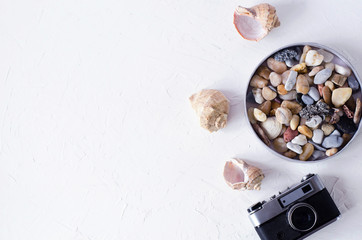 Summer background with camera, shells and sea pebbles.