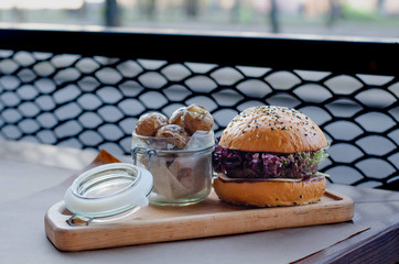 A hamburger with meat and a jar of potatoes stands on the cafe table.