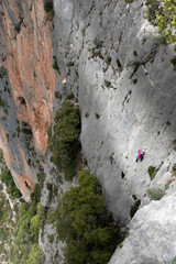 Sport climbing. A person proceeds along an overhanging wall on the precipice of the canyon carved by the stream