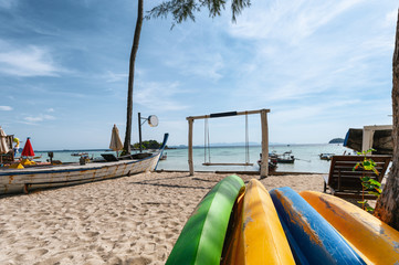 Colorful surfboard with wooden swing on the beach in tropical sea