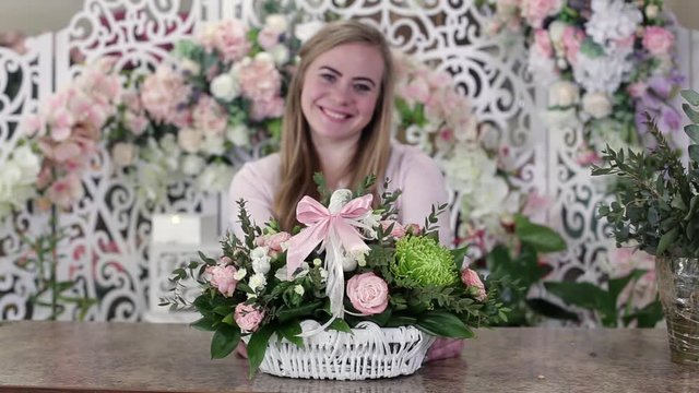 Smiling young florist woman gives a beautiful bouquet of roses to the camera, focus on a bouquet. Flower business concept.