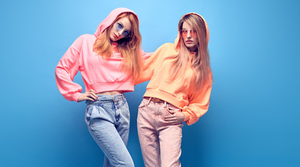 Two Young hipster Woman in Stylish neon hoodie, fashion jeans having fun. Funny adorable...