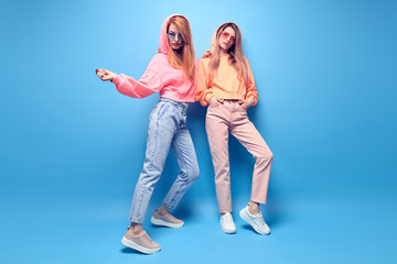 Two hipster Girl in trendy colorful neon fashion Outfit Fooling Around in Studio. Young Tomboy...