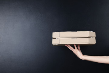 Female hand holding pizza boxes on blackboard background