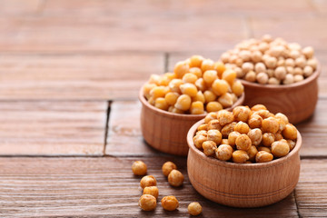 Roasted and dry chickpeas in bowls on brown wooden table