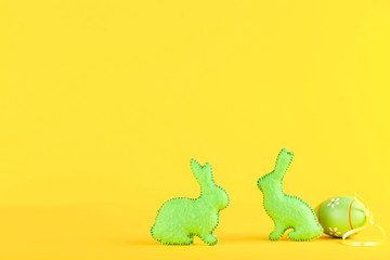 Fabric rabbits with easter egg on yellow background
