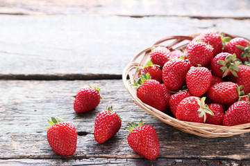 Fresh strawberries in basket on grey wooden table