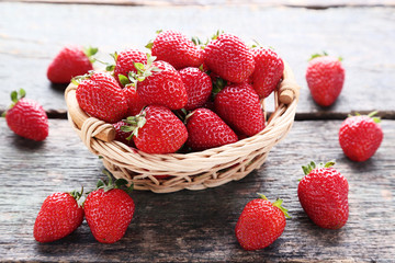 Fresh strawberries in basket on grey wooden table