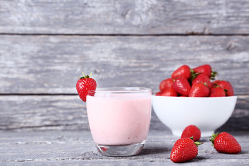 Smoothie in glass with strawberries on grey wooden table