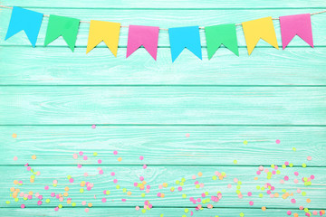 Colorful confetti and paper flags on mint wooden background