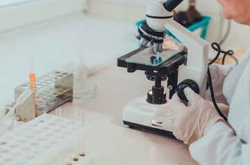 A doctor in a medical laboratory checking blood samples with a microscope. Concept of medical...