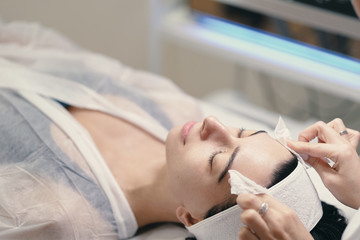 Obraz na płótnie Canvas Female cosmetologist making facial treatment to a beautiful woma