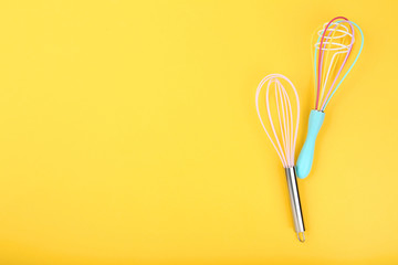 Kitchen whisks on yellow background