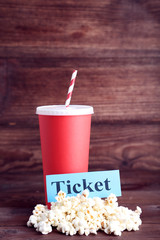 Red paper cup with popcorn and word Ticket on wooden table