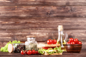 Tasty sandwich with fresh vegetables and spices on brown wooden table