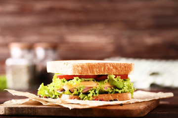 Tasty sandwich with fresh vegetables on brown wooden table