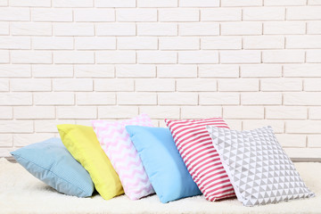 Soft colorful pillows on brick wall background