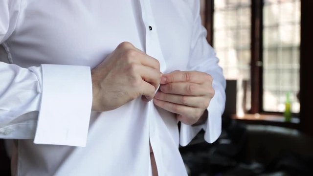 Slow motion buttoning white tux shirt close