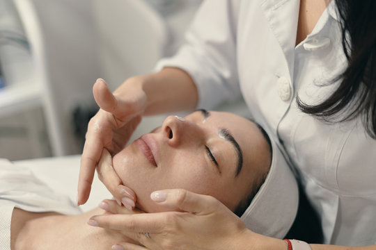 Young woman lies with closed eyes, cosmetologist making procedur