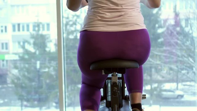 Fat woman intensely exercising on stationary bike