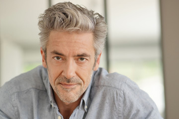 Portrait of handsome mature man looking at camera in contemporary home