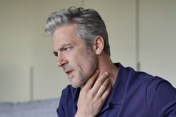 Mature man with sore throat at home