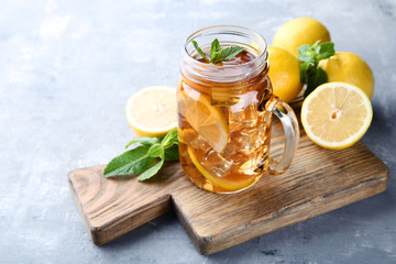 Ice tea in glass jar with lemon and mint leafs on wooden table