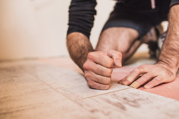 A worker hands knocking on a laminate connecting the panels with a Lock Click