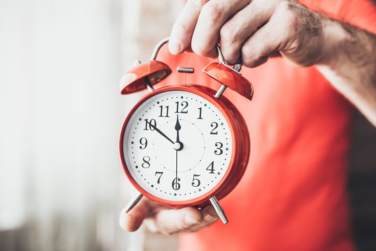 Closeup of a caucasian man adjusting the time of a clock - you can not oversleep or miss important affairs and events
