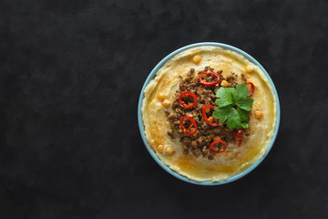 Hummus with spicy mutton minced meat on a black.