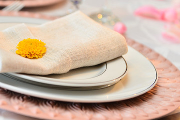 white napkin with yellow flower, peach fuzz sousplat, table set