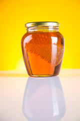 Sweet honey in the comb, glass jar on wooden background