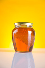 Sweet honey in the comb, glass jar on wooden background
