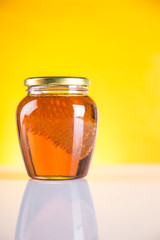 Sweet honey in the comb, glass jar on wooden background