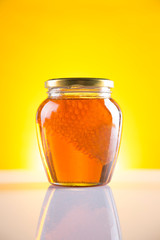 Sweet honey in the comb, glass jar on wooden background