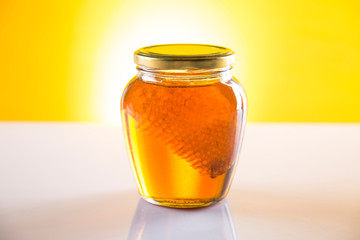 Sweet honey in the comb, glass jar on wooden background
