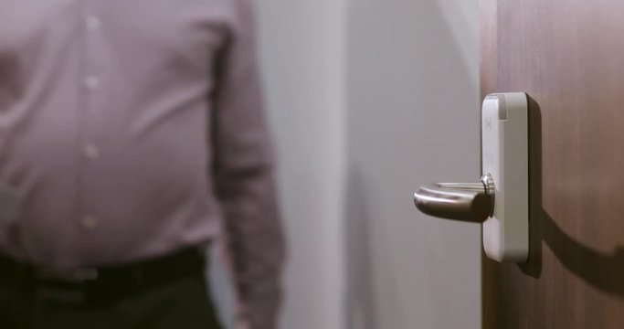 Man comes to the door of the hotel and opens room using an electronic key card. Blur video.