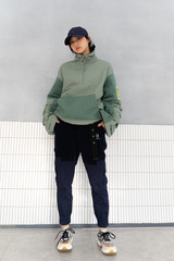 Asian girl weaing a large green jacket with sports shoes, black pants ,looking sharp and cool