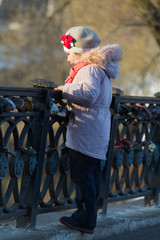 a little girl on a spring walk at the pond fenced with a wrought-iron fence