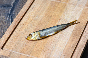 Baltic herring cold smoked on a wooden cutting board.