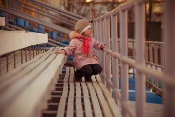 little girl on the stadium stand in Sunny weather in early spring