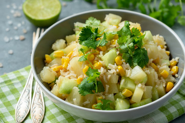 Healthy vegetarian salad with brown rice, corn, cucumber, pineapple and coriander.