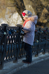 a little girl on a spring walk at the pond fenced with a wrought-iron fence